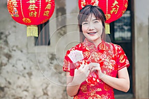 Portrait charming beautiful asian woman wear cheongsam dress up open the red envelope with money, in the Chinese New Year.