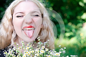 portrait of a charming blonde teenage girl wearing teeth braces with bouquet of white wildflowers. female with braces in