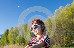 portrait of a charming boy 6 years old in a red striped t-shirt, big sunglasses emotionally joyfully laughing