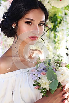 Portrait of a charming brunette bride with sparkling eyes and incredibly beautiful makeup looks at the camera