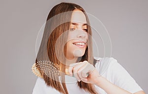 Portrait of charming brunette hair lady combing hair with hairbrush comb, isolated. Young beautiful woman brush long