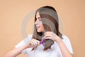 Portrait of charming brunette hair lady combing hair with hairbrush comb, isolated. Young beautiful woman brush long