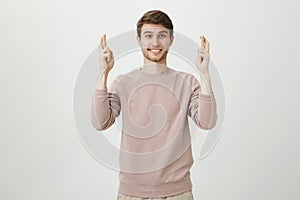 Portrait of charming caucasian male with bristle raising hands with crossed fingers and smiling, expressing willingness