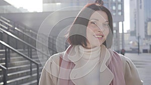 Portrait of charming caucasian woman looking at camera and smiling. Beautiful brunette business lady standing in sunlight