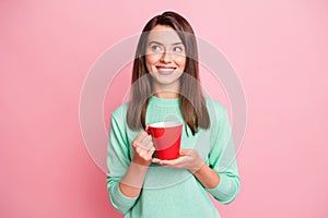 Portrait of charming cheerful minded girl drinking beverage overthinking isolated over pink pastel color background