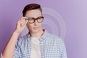 Portrait of charming cool guy adjust glasses look side blank space on violet background