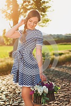 Portrait of charming girl with a basket of flower on the road