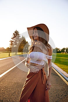 Portrait of charming hipster woman in straw hat over road