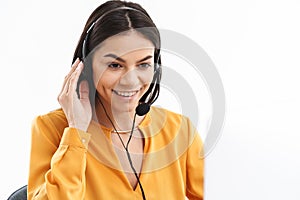 Portrait of charming hotline assistant woman wearing microphone headset speaking with customer by phone in office