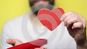 Portrait of charming man holds hand paper heart shaped card