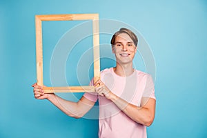 Portrait of charming positive guy show wooden brick handmade frame for picture photo wear casual style clothing isolated