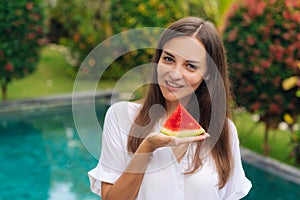 Portrait of charming smiling girl holding slice of juicy watermelon in her hand