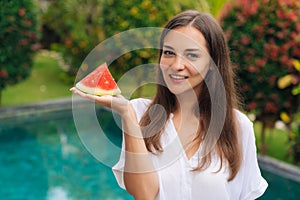 Portrait of charming smiling girl holding slice of juicy watermelon in her hand