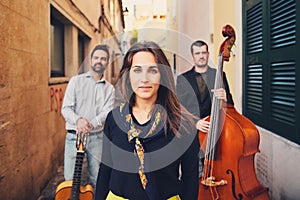 Portrait of a charming smiling girl in old street. Against the background of two musicians with a guitar and double bass. Cute wom