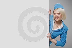 Portrait of charming stewardess wearing in blue uniform. Empty billboard