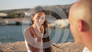 Portrait of charming teenage girl tasting plum smiling listening to man talking. Confident cheerful Caucasian teenager