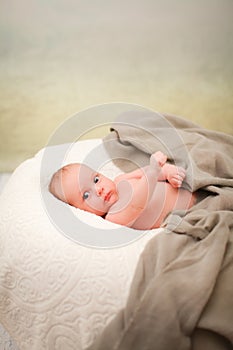 Portrait of charming two month caucasian baby on white plaid indoor in selective focus