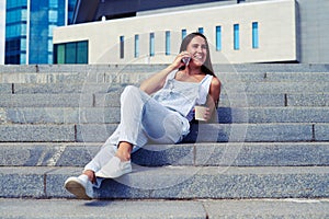 Portrait of charming woman in overalls resting on stairs and ch