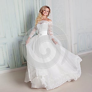 Portrait of charming woman in wedding dress. Dancing on the background walls with classic moldings