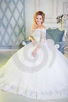 Portrait of charming woman in wedding dress. The girl bride sits in a chair