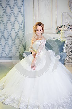 Portrait of charming woman in wedding dress. The girl bride sits in a chair