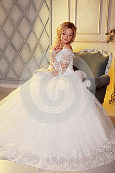 Portrait of charming woman in wedding dress. The girl bride sits in a chair