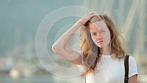 Portrait of charming young tourist woman on the Mediterranean coast. Attractive red-haired girl walking by the sea shore