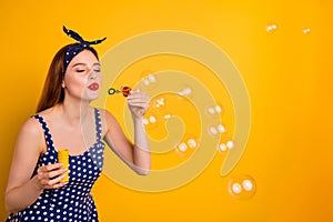 Portrait of charming youth have free time hold hand blow bubbles isolated over yellow background