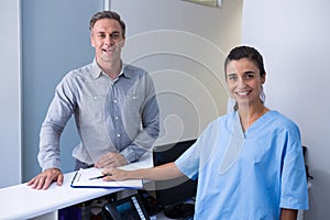 Portrait of cheeful doctor and man standing at desk
