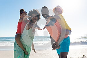 Portrait of cheerful african american parents and children with arms outstretched at beach