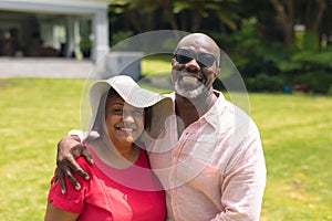 Portrait of cheerful african american senior couple standing together in backyard on sunny day