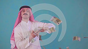 Portrait cheerful Arab man with a mustache and traditional clothes with Audi ,throws money