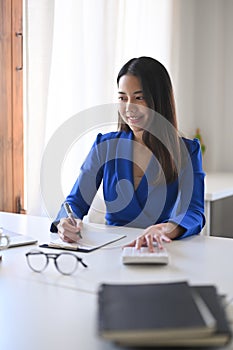 Cheerful asian business woman working in bright office.