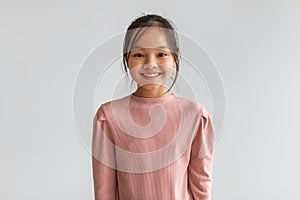 Portrait Of Cheerful Asian Kid Girl Posing On Gray Background