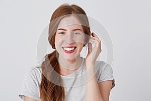 Portrait of cheerful attractive young woman with red hair and freckles feels happy and smiling isolated over white background