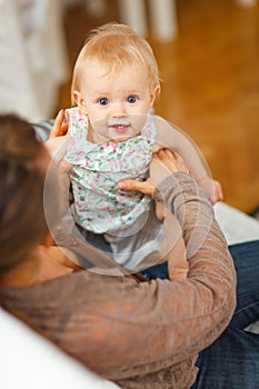 Portrait of cheerful baby playing on mamas knees