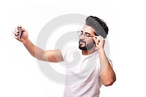 Portrait of a cheerful bearded arab man taking selfie over white background