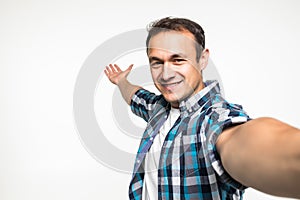 Portrait of a cheerful bearded man taking selfie over white background
