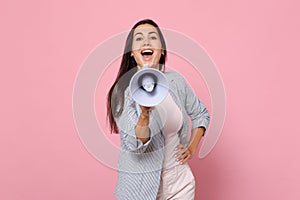 Portrait of cheerful beautiful funny young woman in striped jacket scream in megaphone isolated on pink pastel wall