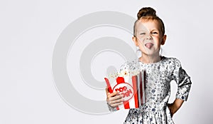 Portrait of a cheery pretty girl holding plastic cup and eating popcorn isolated over white background