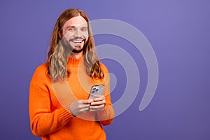 Portrait of cheerful blond hair guy wear orange stylish pullover he bought using smartphone on ebay isolated over violet