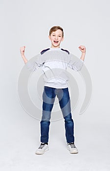 Portrait of cheerful boy celebrating victory at studio background