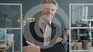 Portrait of cheerful businessman standing in workplace with arms crossed and smiling looking at camera