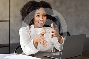 Portrait of cheerful businesswoman sitting at desk in modern office