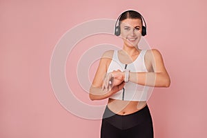 Portrait of cheerful caucasian girl wearing sportswear and listening music over pink backdrop