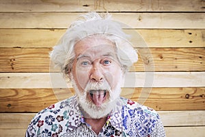 Portrait of cheerful caucasian senior crazy man with wood background - alternative and young old male in funny expression -white
