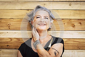 Portrait of cheerful caucasian senior happy woman with wood background - alternative and young old female smile and enjoy -
