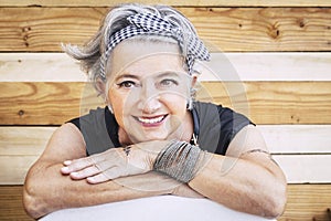 Portrait of cheerful caucasian senior happy woman with wood background - alternative and young old female smile and enjoy -