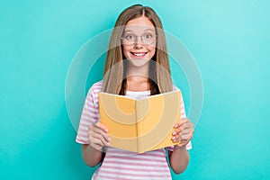 Portrait of cheerful clever girl toothy smile arms hold book isolated on aquamarine color background