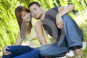 Portrait of cheerful couple sitting under the tree